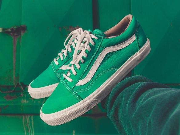 person holding pair of green Vans shoes