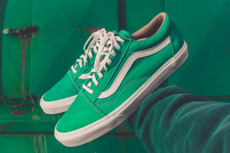 person holding pair of green Vans shoes